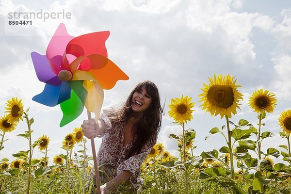 Frau hält Windmühle im Sonnenblumenfeld