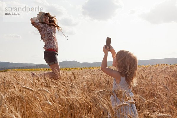 Mädchen fotografiert Mutter im Weizenfeldspringen