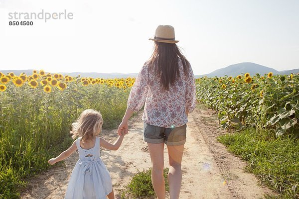 Mutter und Tochter beim Spaziergang durch das Sonnenblumenfeld