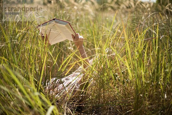 Frau in langem Gras liegend Lesebuch