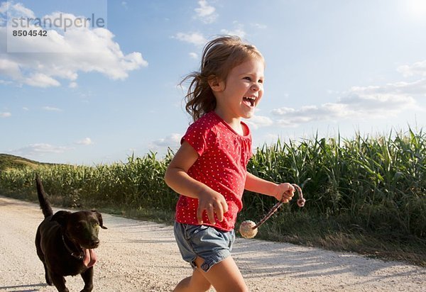 Mädchen und Hund rennen durchs Feld
