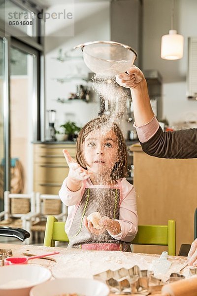 Mutter und Tochter beim Mehlsieben in der Küche