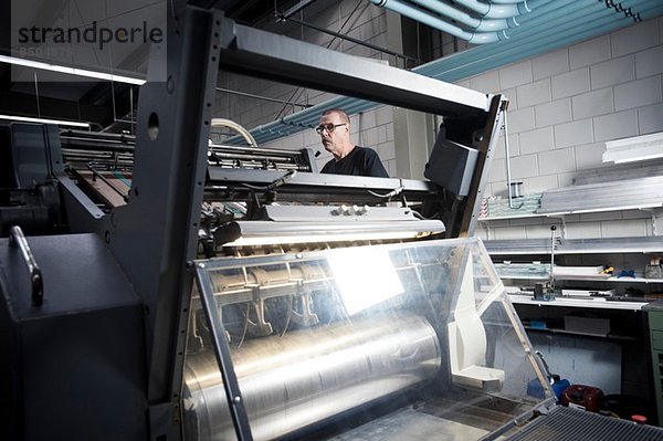 Arbeiter beim Bedienen der Druckmaschine in der Druckerei