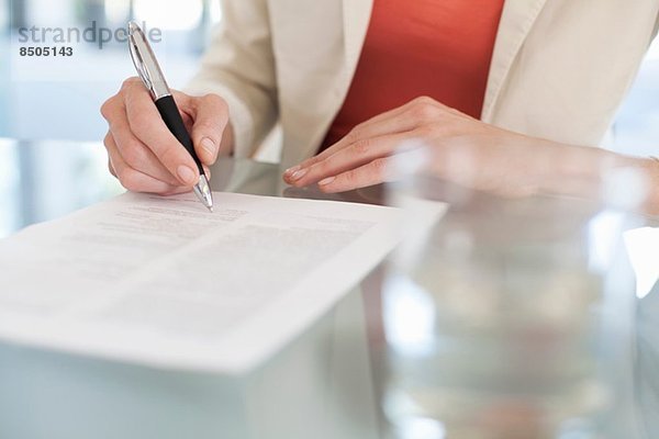 Abgeschnittenes Bild der Geschäftsfrau beim Unterschreiben von Papierkram