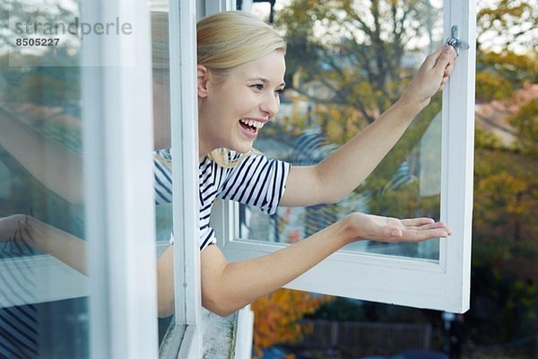 Junge Frau  die sich aus dem Fenster lehnt