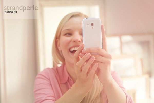 Junge Frau beim Selbstporträtfotografieren mit dem Smartphone