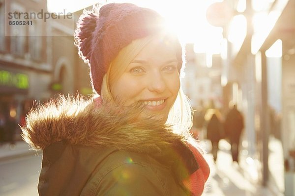 Porträt einer jungen Frau mit Strickmütze  über die Schulter schauend