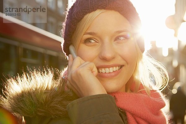 Portrait einer jungen Frau mit Strickmütze  Telefonanruf