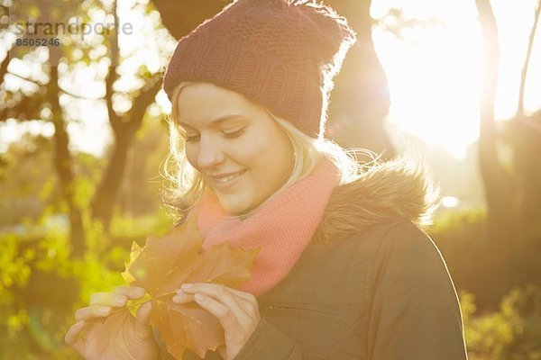 Porträt einer jungen Frau im Park mit Herbstblatt