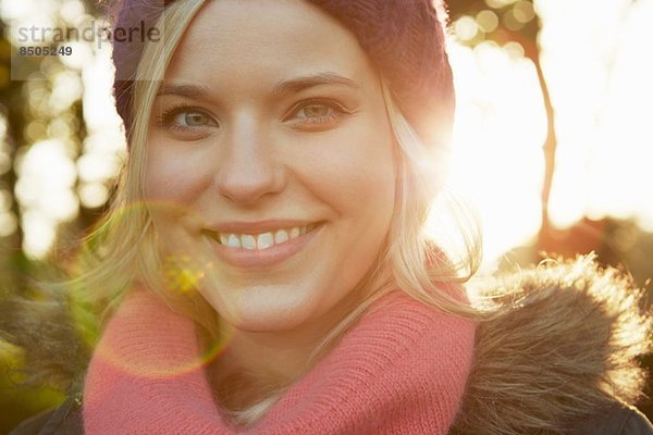 Portrait einer jungen Frau im Park mit Strickmütze und Schal