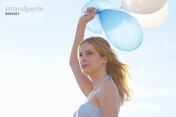 Porträt einer jungen Frau  die Luftballons hochhält.