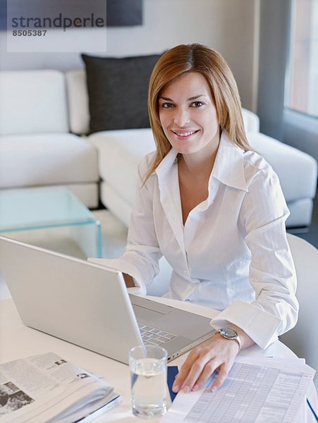 Junge Geschäftsfrau bei der Arbeit am Computer im Hotelzimmer