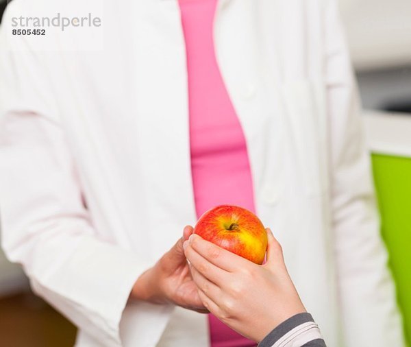 Zahnarzt gibt Mädchen Apfel  Nahaufnahme