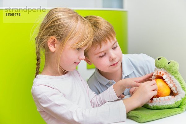 Zwei Kinder spielen mit Spielzeugkrokodil
