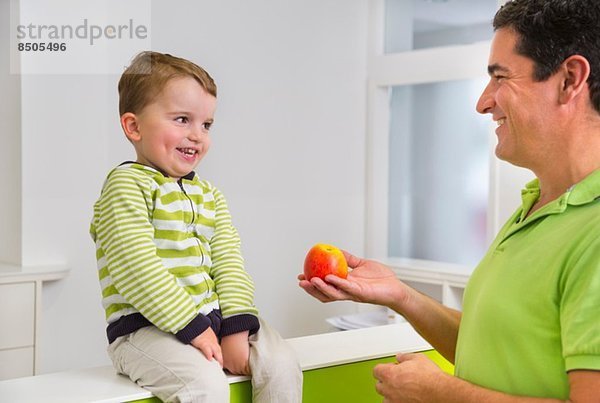 Mann schenkt dem Jungen Apfel