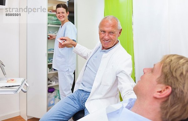 Männlicher Zahnarzt behandelt männlichen Patienten