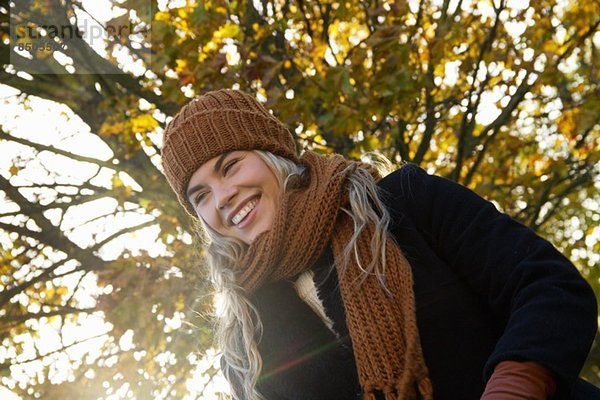 Lächelnde junge Frau im herbstlichen Park eingehüllt