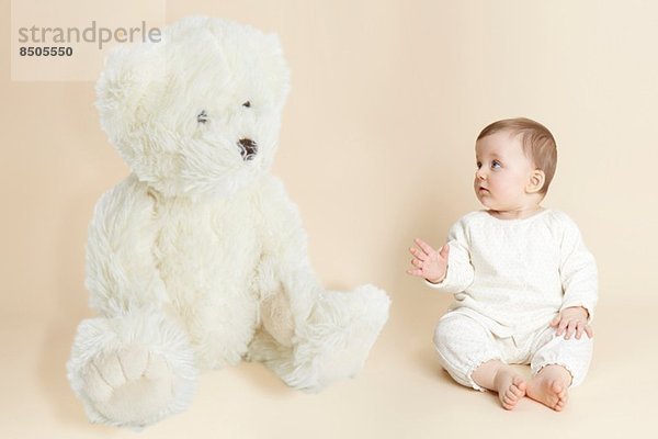 Studio-Porträt des Mädchens neben dem riesigen Teddybären