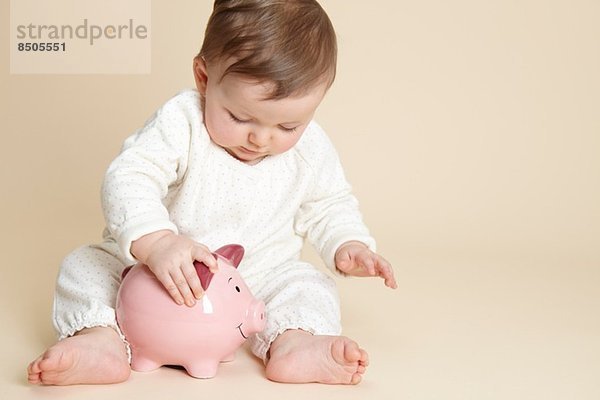 Studio-Porträt des Mädchens beim Spielen mit dem Sparschwein