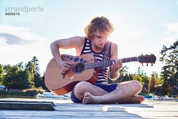 Junger Mann spielt Gitarre am Pier  Gavle  Schweden