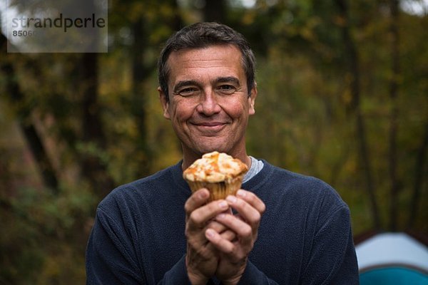 Erwachsener Mann im Wald mit Muffin