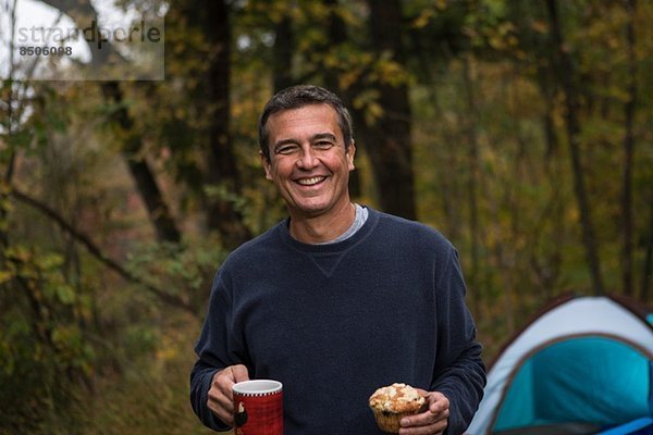 Reifer Mann im Wald mit Muffin und Heißgetränk