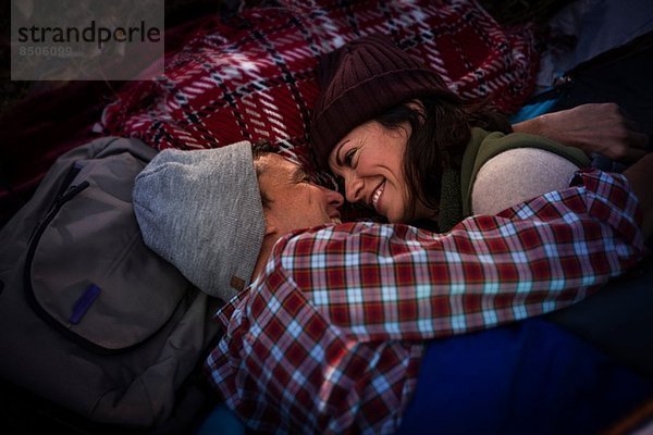 Erwachsene Paare liegend  umarmen sich auf einem Picknickteppich