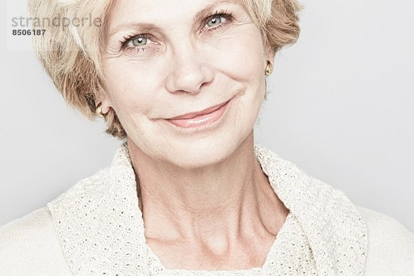 Abgeschnittenes Studioporträt einer lächelnden Seniorin