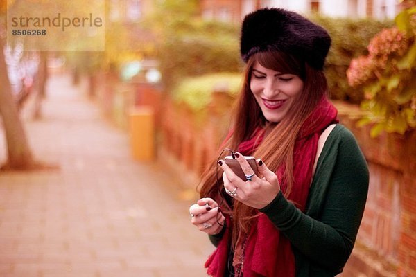 Junge Frau trägt Winterkleidung  hält Smartphone