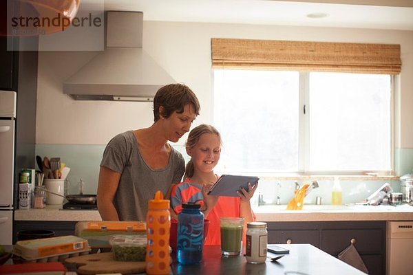 Mutter und Tochter beim Betrachten des digitalen Tabletts in der Küche
