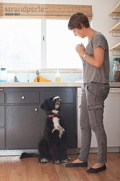 Reife Frau und ihr Hund in der Küche