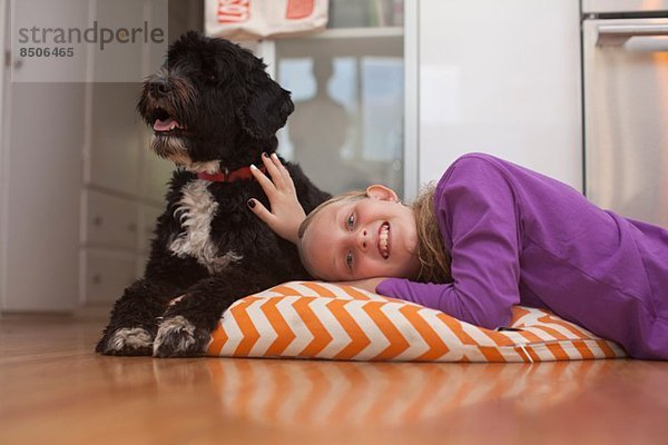 Porträt eines auf Kissen liegenden Mädchens mit Haushund