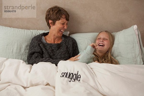 Mutter und Tochter lachend im Bett