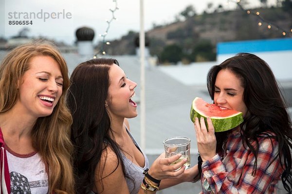 Drei junge Frauen beim Grillen mit großer Melonenscheibe