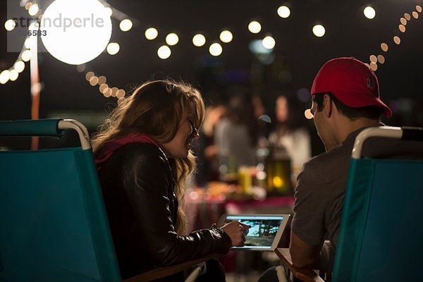 Junges Paar schaut auf digitales Tablett am Dachgrill