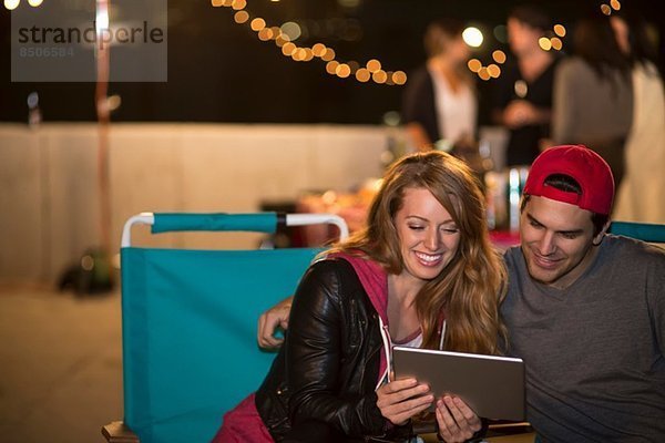 Junges Paar mit digitalem Tablett am Dachgrill