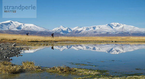Wanderer am Khurgan Nuur  gespiegelt im See vor Bergkulisse des Altaigebirges  Grenzgebiet zu China  Altai-Tawan-Bogd-Nationalpark  Tsengel  Bajan-Ölgii  Hochaltai  Mongolei