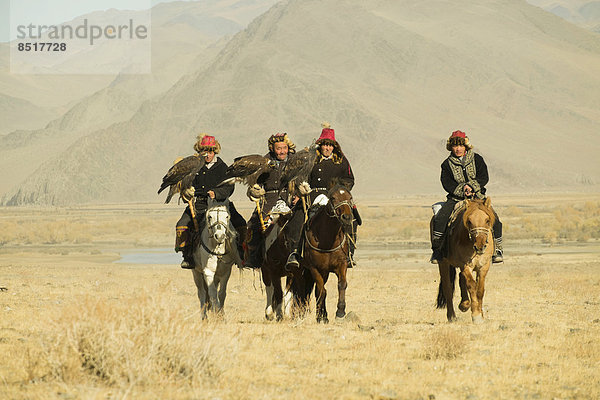 Vier kasachische Adlerjäger auf ihren Pferden auf dem Weg zum Adlerfest in Sagsai  Bayan-Ölgii Aimag  Mongolei