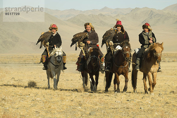 Vier kasachische Adlerjäger auf ihren Pferden auf dem Weg zum Adlerfest in Sagsai  Bayan-Ölgii Aimag  Mongolei