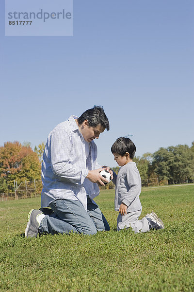 Außenaufnahme Menschlicher Vater Sohn Hispanier Fußball freie Natur spielen