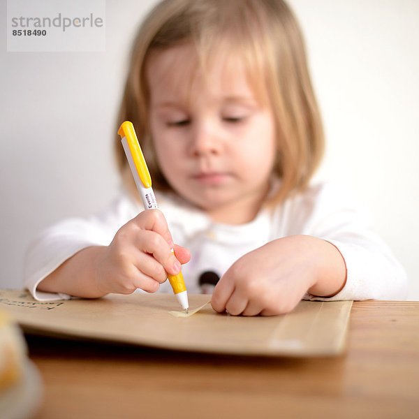 Ein Kind hält einen Kugelschreiber in der Hand und malt.