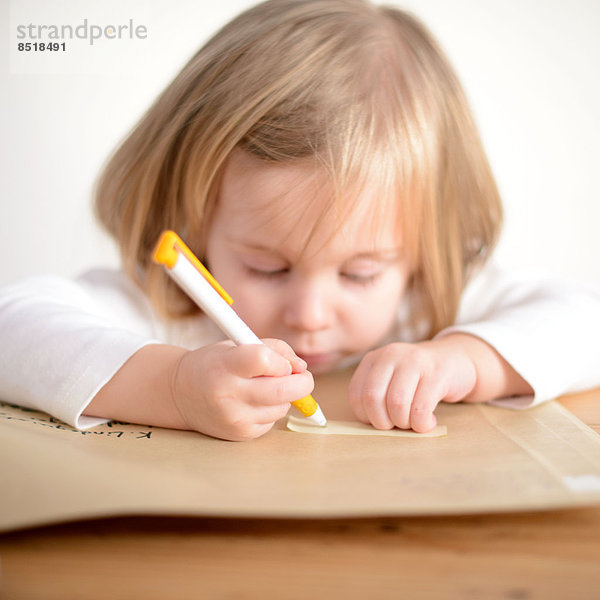 Ein Kind hält einen Kugelschreiber in der Hand und malt.