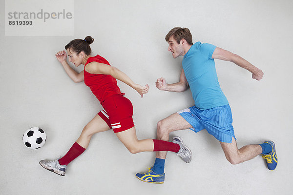 Man and woman running after football