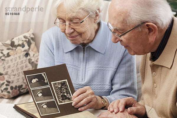 Seniorenpaar beim Betrachten des alten Fotoalbums zu Hause