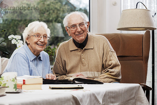 Seniorenpaar beim Betrachten alter Fotos zu Hause