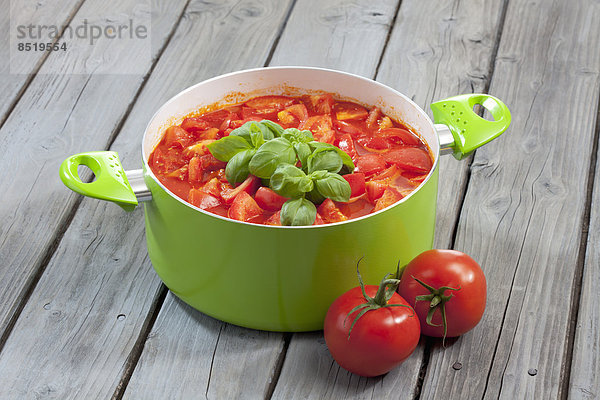 Kochtopf mit Tomatenstücken und Basilikum