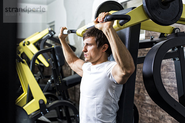 Austria  Klagenfurt  Man in fitness center doing machine workout
