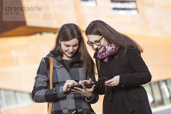 Zwei junge Frauen mit digitalem Tablett im Freien