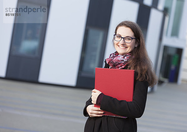 Smiling student with folder outdoors  portrait