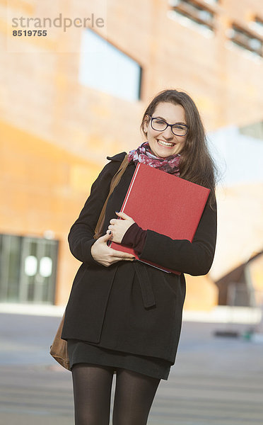 Lächelnder Student mit Mappe im Freien  Portrait